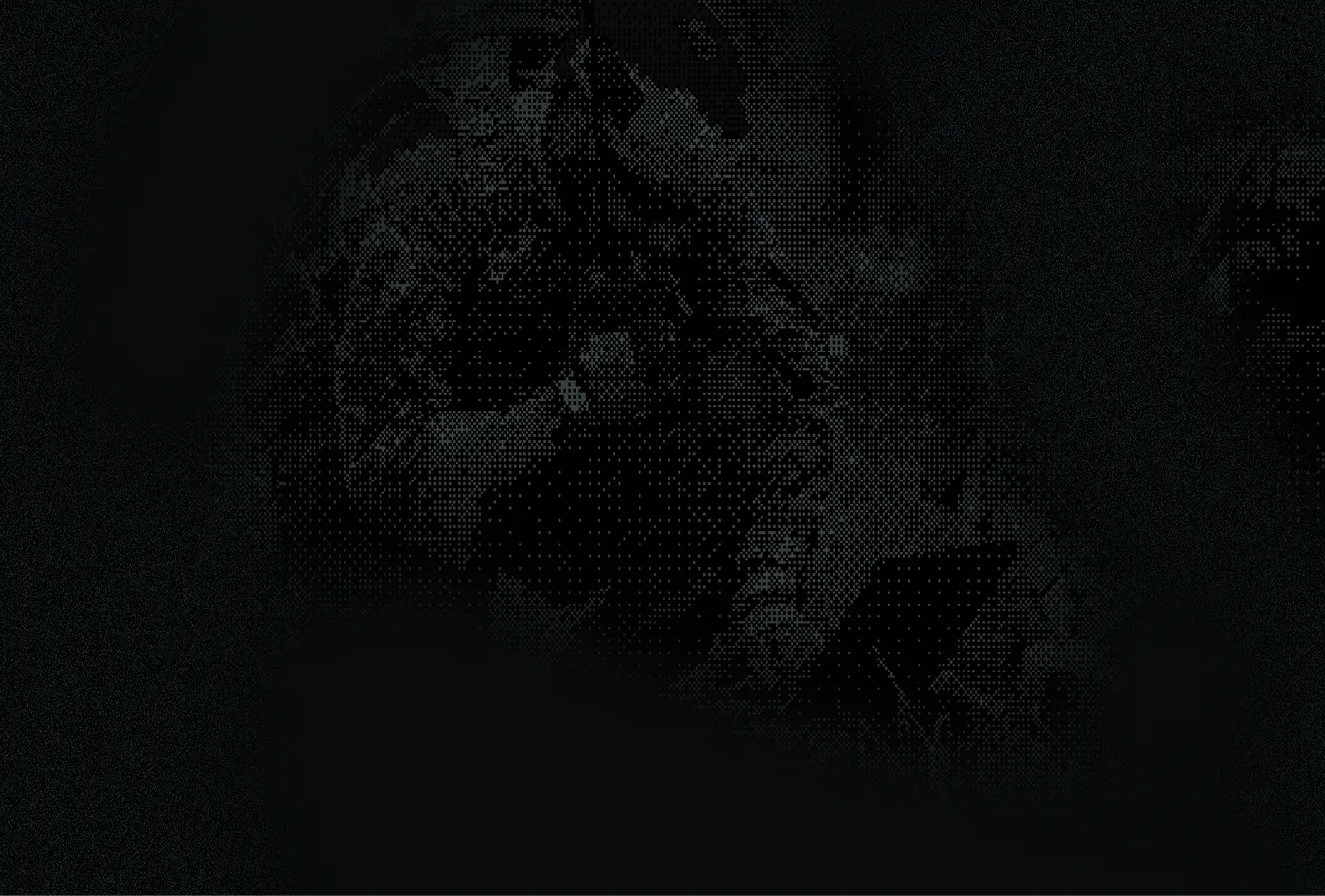 Soldier in camouflage gear kneeling and working on a laptop in a dark environment.